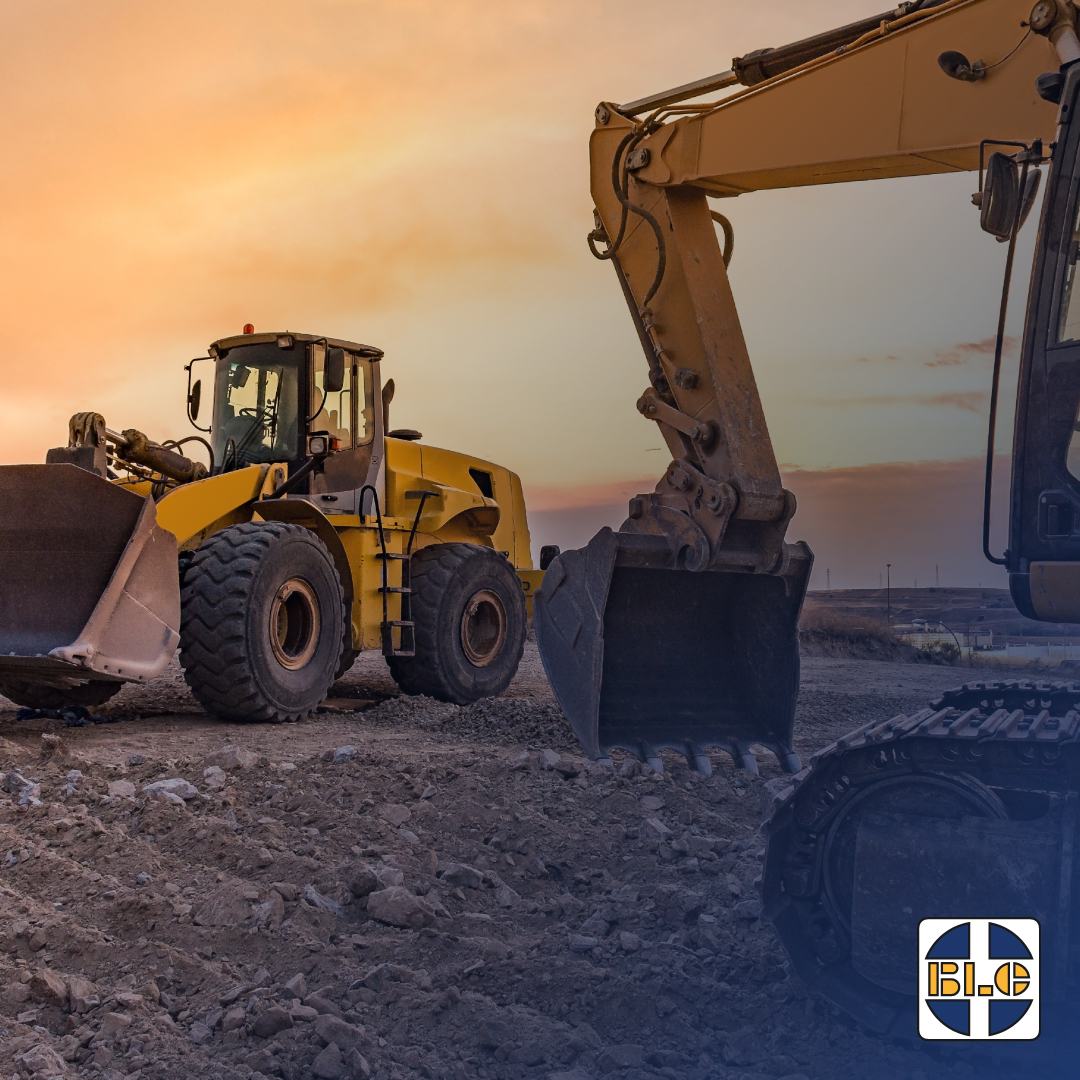 Wheel loader and excavator on an earthmoving site at sunset with BLC branding
